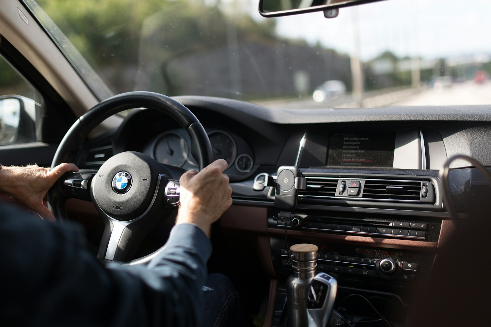 person holding BMW steering wheel, auto